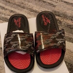 Reebok Classic Slides in black with a red footbed and branding. 